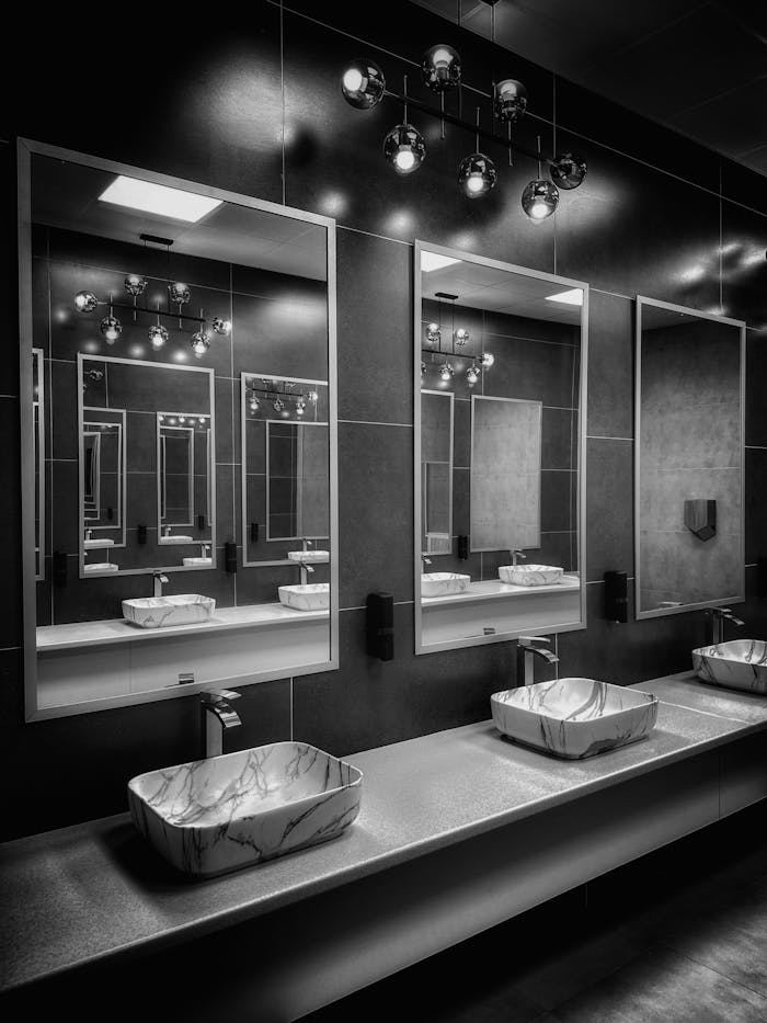 why-choose-us Black and white modern bathroom with stylish mirrors and lighting.