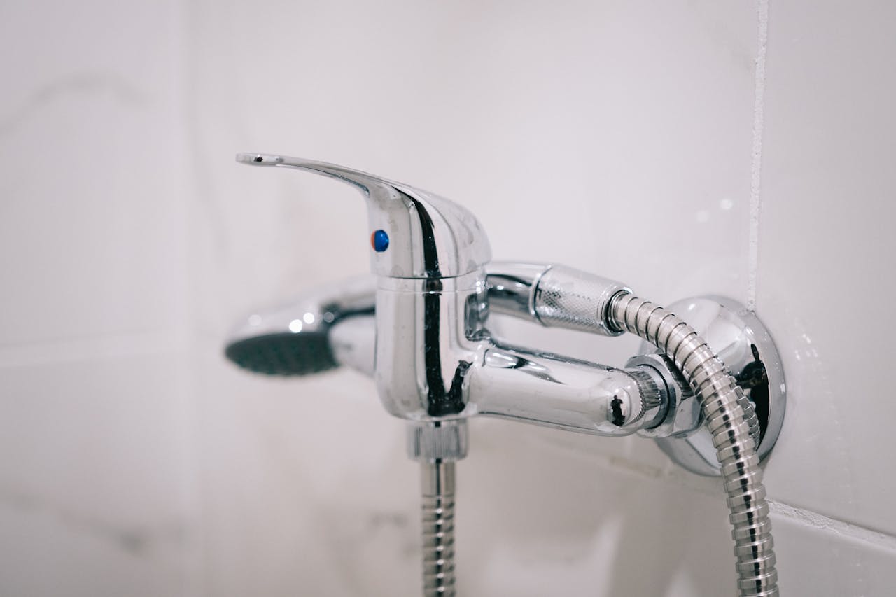 A detailed view of a sleek chrome shower faucet in a clean bathroom setting.