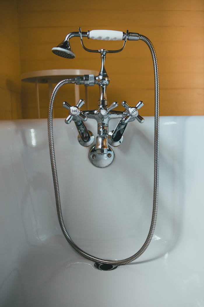 Elegant chrome vintage faucet and shower head in a white bathtub.